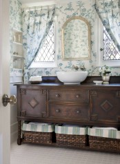 a neutral and elegant guest toilet with a vntage dark-stained vanity, a vessel sink, a mirror and floral print curtains