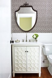 a simple guest toilet with printed wallpaper, white tiles, a white textural vanity and a mirror in a dark frame