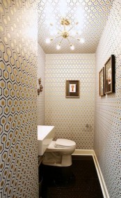a stylish mid-century modern toilet with geometric wallpaper, a square sink and a sunburst chandelier