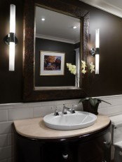 a monochromatic guest toilet with dark brown and white walls, a semi circle vanity, a large mirror and lamps