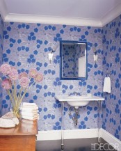 a chic blue and white guest toilet with floral print wallpaper, a wooden storage unit and a sink