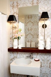a neutral modern guest toilet with a mirror, some lamps on a shelf and a wall-mounted sink