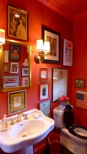 a bold guest toilet with bright orange walls, a free-standing sink, a mirror and a whole gallery wall