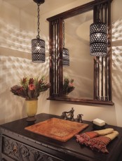 a Moroccan-inspired space with hanging lanterns, a mirror in a wooden frame, a dark-stained wooden vanity