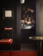 a moody guest toilet with a vanity and a stone sink, a mirror in a metallic geometric frame