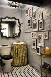 an eclectic bathroom with painted brick walls, a mirror in a vintage frame, a gallery wall and a vanity covered with a fabric curtain