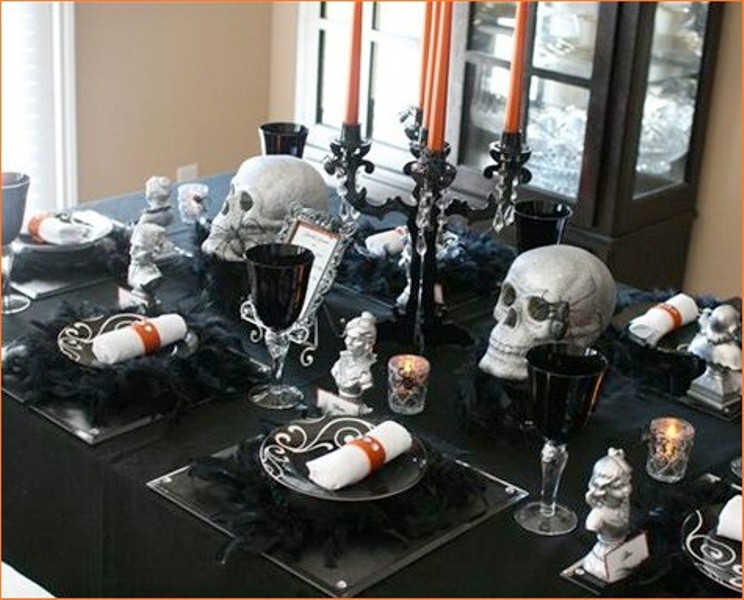 a glam Halloween party tablescape in black, with black candleabras and silver skulls, black placemats, chargers and plates, black glasses and candles is wow