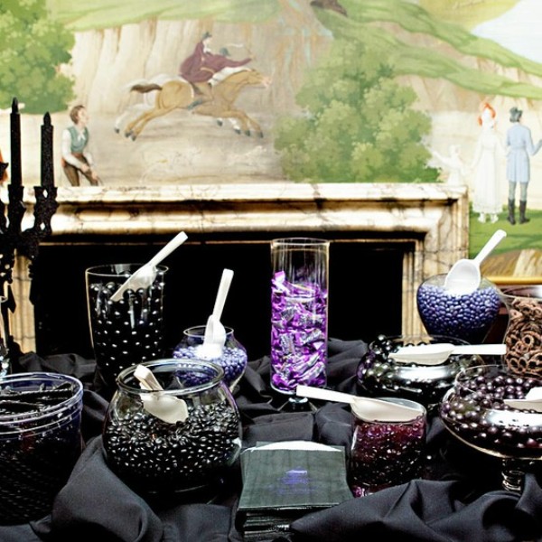 a black candy bar with bowls and plates with black candies, desserts and a black candlelabra with black candles
