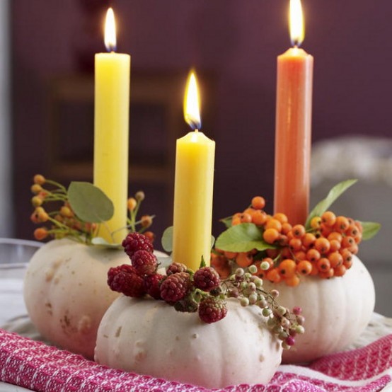 white pumpkins with berries, leaves and colorful candles are pretty decorations for fall or Thanksgiving