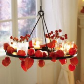 a chandelier with dried blooms, berries and candles is a bold and rustic decoration to rock for fall or Thanksgiving