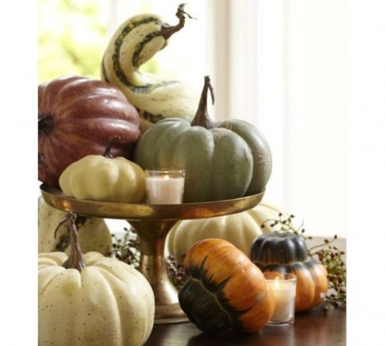 a fall centerpiece of a gold stand with pumpkins, gourds and candles around is a pretty piece to rock in fall or Thanksgiving