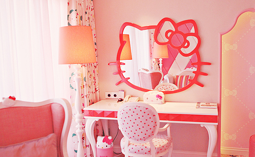 a bold Hello Kitty bedroom with a red and white desk, a pink chair, a Hello Kitty mirror, a bold pink sofa
