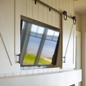 a white wood clad wall with a niche for a TV and barn doors hiding the TV are a cool combo for a rustic or barn interior