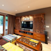 a large TV unit and a TV on the wall, with refined laser cut woodne panels that add interest and chic to the space