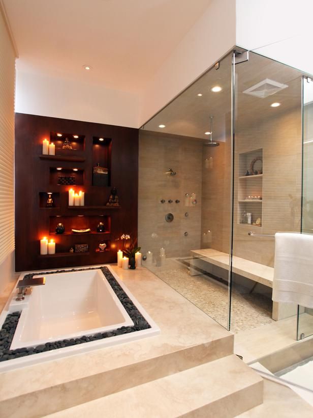 a welcoming neutral home space with a large shower space with a bench, a built in bathtub surrounded with pebbles, niches with candles is a fantastic space