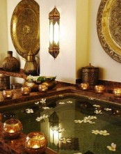 a jaw-dropping Asian home space with a large tub or plunge pool clad with tiles, candleholders surrounding the tub, Eastern style lanterns on the wall just wows