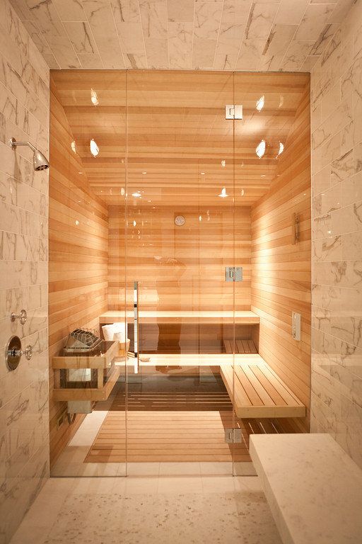 a contemporary refined home space with a shower space clad with marble tiles and a sauna done with wood, with built-in lights is amazing