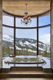 a gorgeous home space with a curved window, a fantastic mountain view, a built-in tub and a crystal chandelier