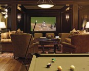 an elegant home theater room with a screen clad with dark-stained wood, beige and tan seating furniture, a dark-stained table and a pool table