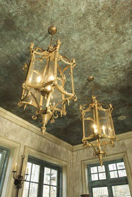 a stylish and chic vintage ceiling done with green printed wallpaper and gorgeous gold pendant lamps that remind of lanterns