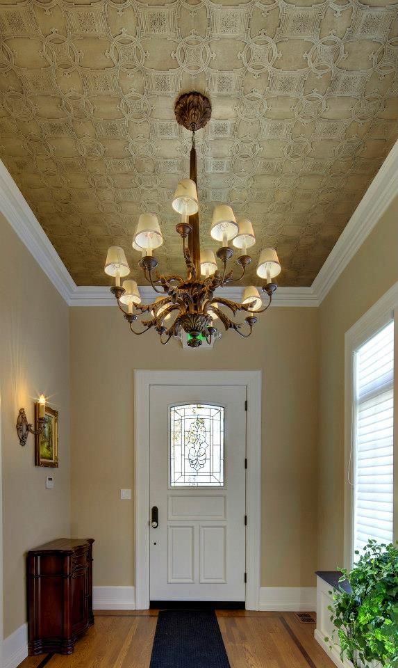 a lovely gold vintage inspired ceiling done with wallpaper and with a large and heavy vintage inspired chandelier
