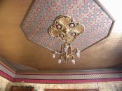 a beautiful vintage ceiling done with metallic paint, with a hexagon with colorful printed wallpaper and a beautiful gold chandelier is amazing