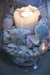 a cool decoration of a glarge glass, seashells and a candle in the center is a cool and easy DIY