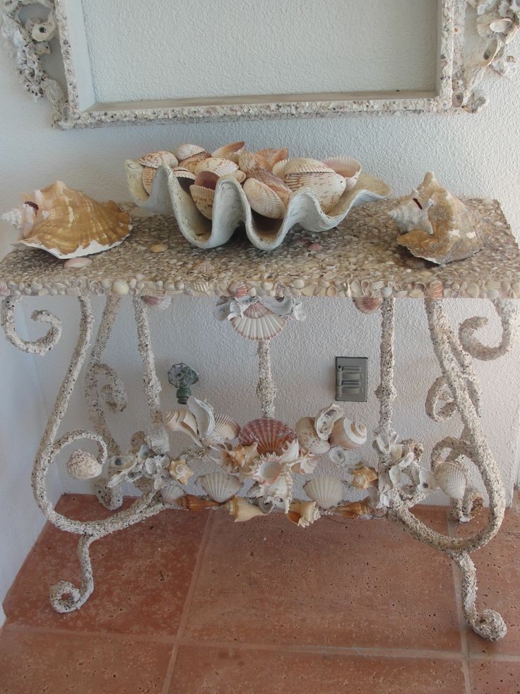 a vintage and elegant console table with seashells   decorated with them and with seashells on it for a coastal feel