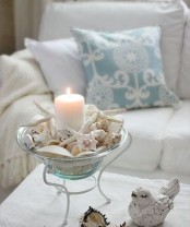 a cool seashell decoration – a blue glass bowl with seashells, starfish and a large candle inside it