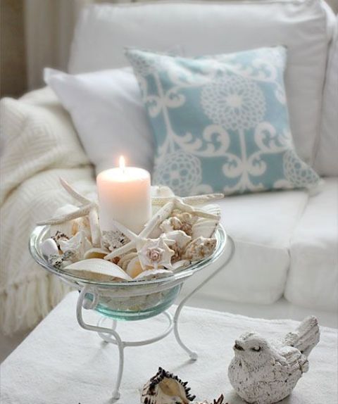 a cool seashell decoration - a blue glass bowl with seashells, starfish and a large candle inside it