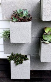 a cement wall with built-in planters with greenery and succulents is a stylish outdoor decoration to go for