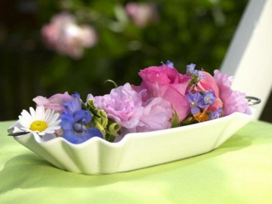 a white bowl with some colorful flower heads is a cool bright centerpiece or decoration for a vintage space