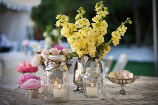jars and a vintage silver teapot with bright summer blooms and candles for a cool bright summer centerpiece