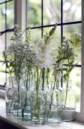 a stack of clear bottles with white blooms will give an ethereal and airy touch to your space, with a boho feel