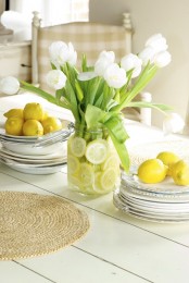 a white jar with white tulips and citrus slices inside is a simple and cool spring centerpiece for every space
