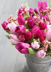 a bucket with pink and fuchsia tulips and pink cherry blossom is a bold rustic decoration for indoors and outdoors with a gorgeous aroma