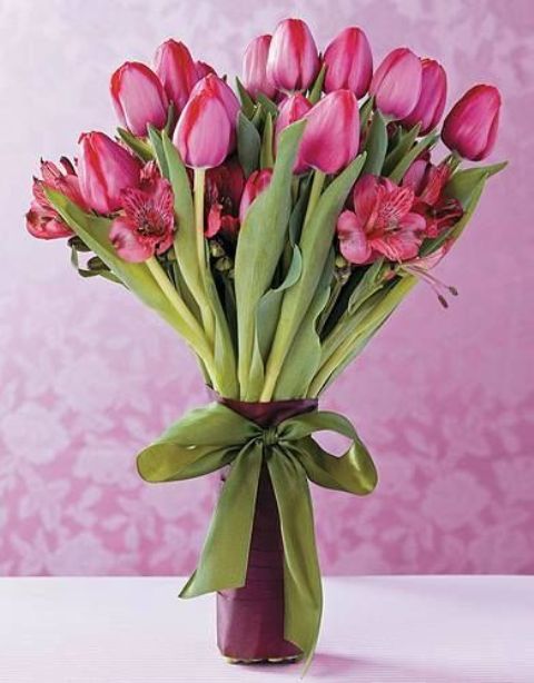 an arrangement of pink tulips with a green bow is a cool spring decoration with a splash of color