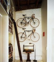 holders attached to the wall and holding the bikes is a lovely idea to store them in a decorative and stylish way, and add interest to the space