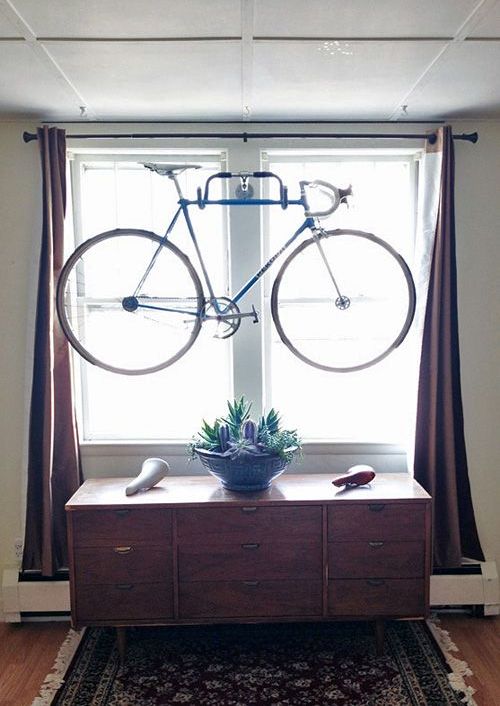 an old bike handle bar attached to the wall between windows can hold a bike and can make storing it a creative decor element