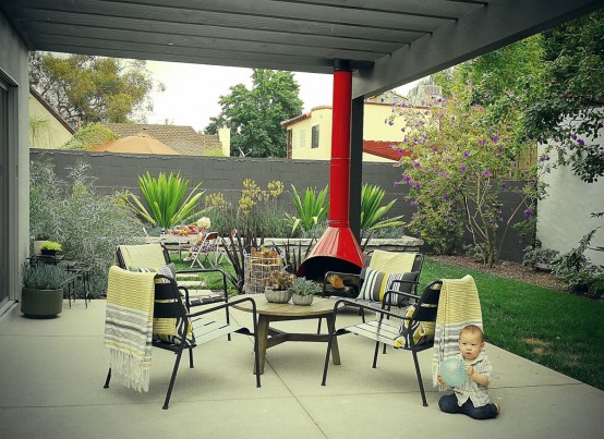 a welcoming modern outdoor living room with a red Malm fireplace, black metal chairs and printed blankets, a low coffee table is welcoming