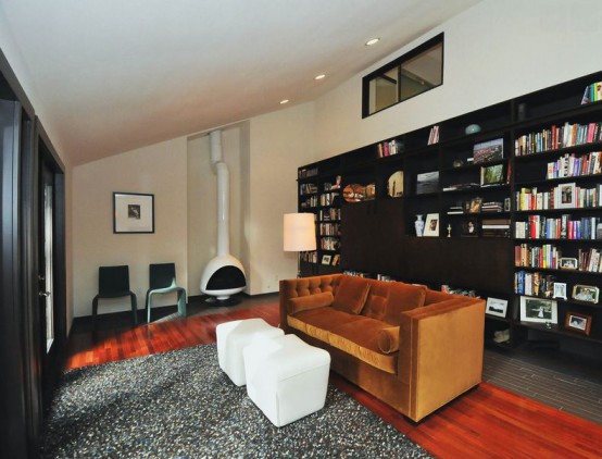 a modern living room with large black bookcases, a rust-colored sofa, white stools and a white Malm fireplace to add coziness to the room