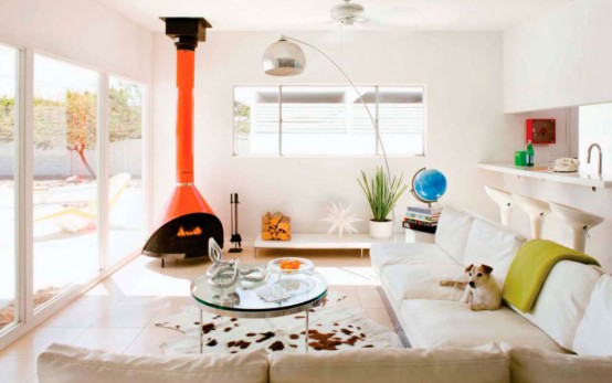 a neutral living room with neutral seating furniture, a glass coffee table, a mustard blanket and an orange Malm fireplace that add color to the room