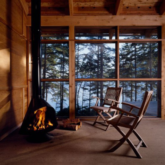 a cozy rustic sitting nook with a black Malm fireplace and wooden chairs plus a forest view is a very lovely space to spend time in