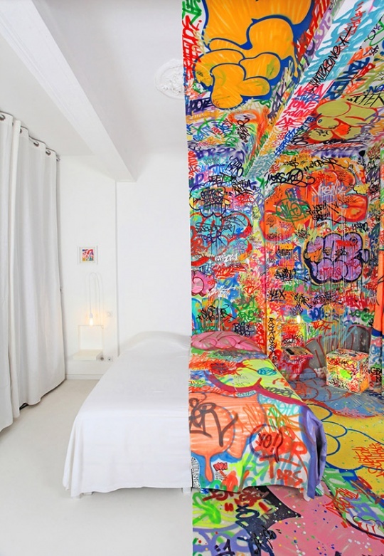 a unique bedroom done partly in white, partly in bold graffiti, and this border goes in the center of the bed, and bedding is half white and half graffiti too