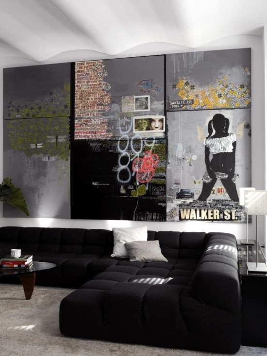 a moody contemporary living room with black seating furniture and a whole wall taken by graffiti to make the space look bolder and cooler