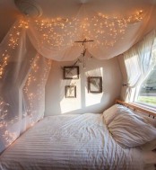 a dreamy sleeping space with a bed with neutral bedding and a canopy over the bed accented with string lights is amazing