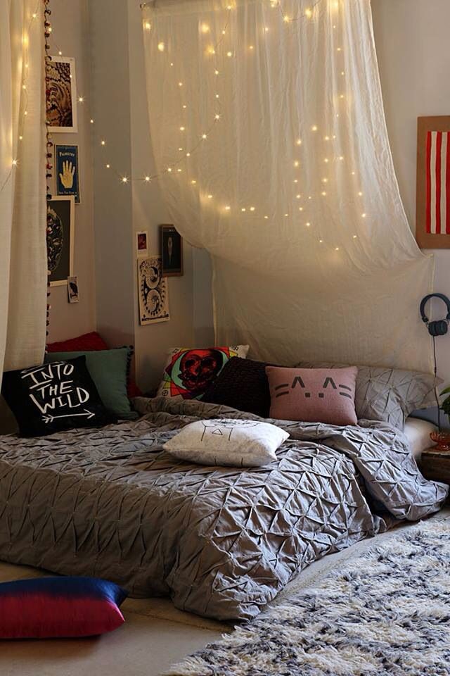 a cool teen bedroom with a low bed and printed bedding, neutral and semi sheer curtains with integrated string lights to form a dreamy canopy over the sleeping space