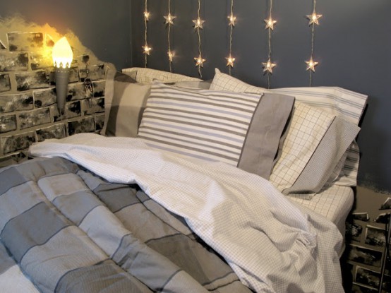 a cozy grey bedroom with a bed with grey and neutral bedding, star-shaped string lights over the bed forming a cozy and lovely headboard