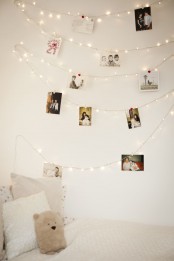 a cozy neutral bedroom with string lights that are used to hang some pics and form a simple gallery wall this way, a great idea for a kid’s room