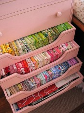 a pink dresser with drawers for storing colorful fabric for crafting